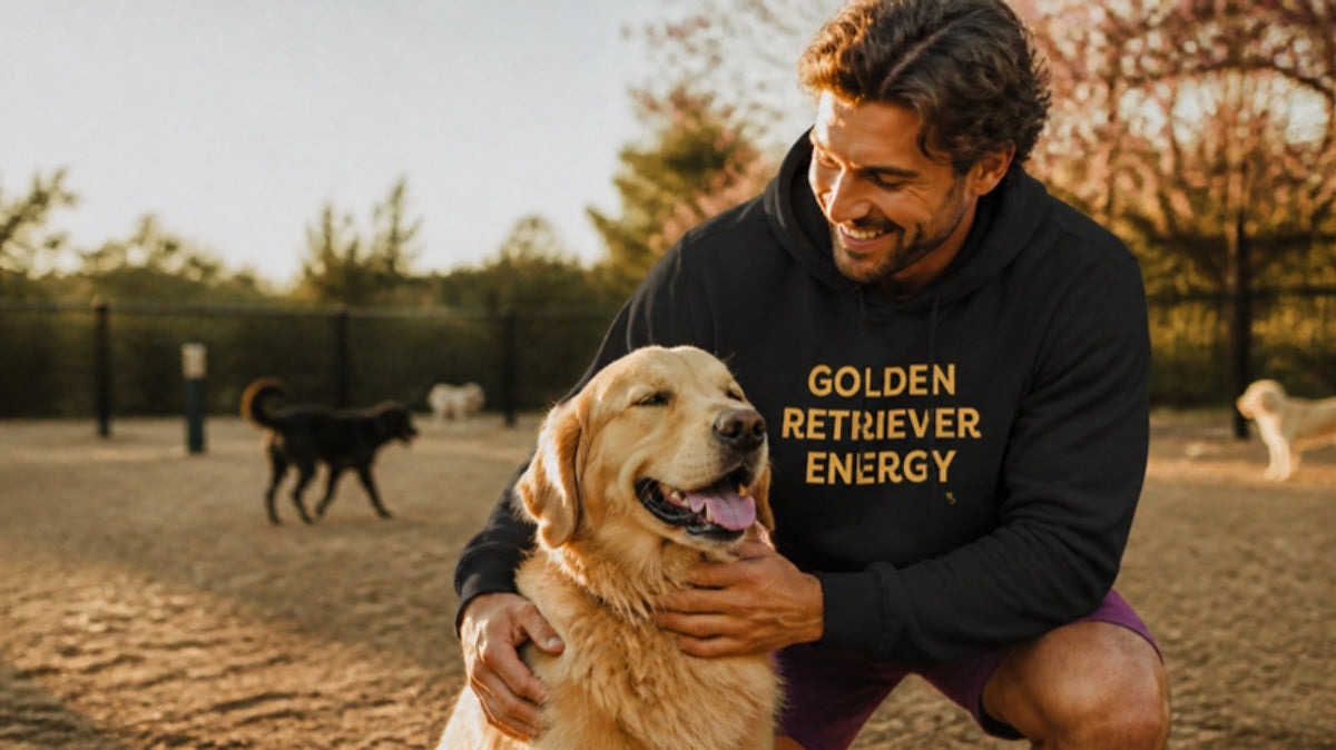 Man in the Golden Retriever Energy hoodie hugging his golden retriever at the dog park