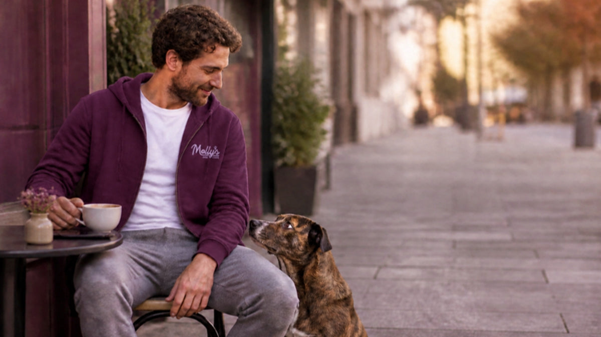 Man in the plum Molly's zip hoodie at a cafe with his dog